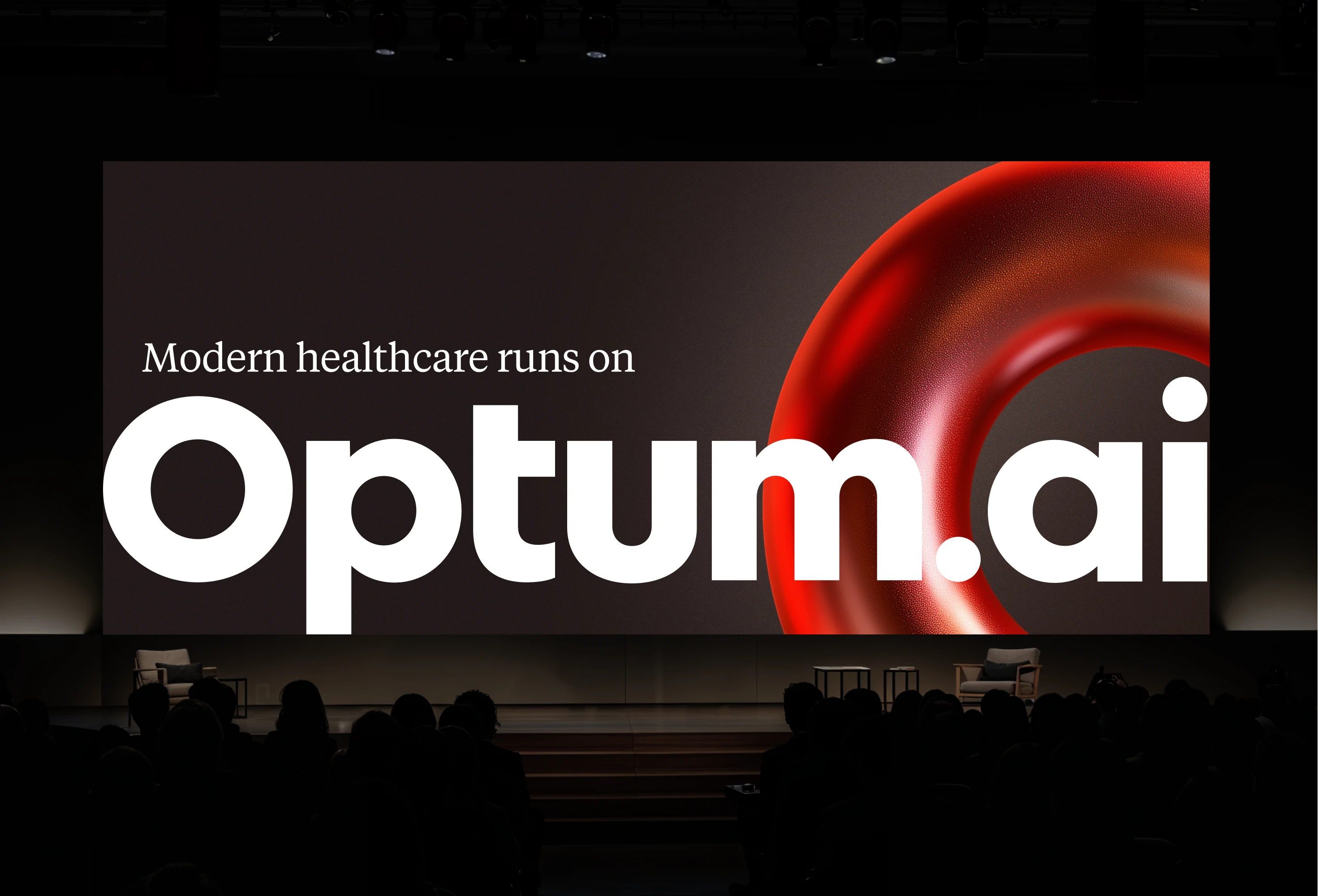OptumAI stage presentation with Modern healthcare runs on OptumAI and a red sculptural ring.