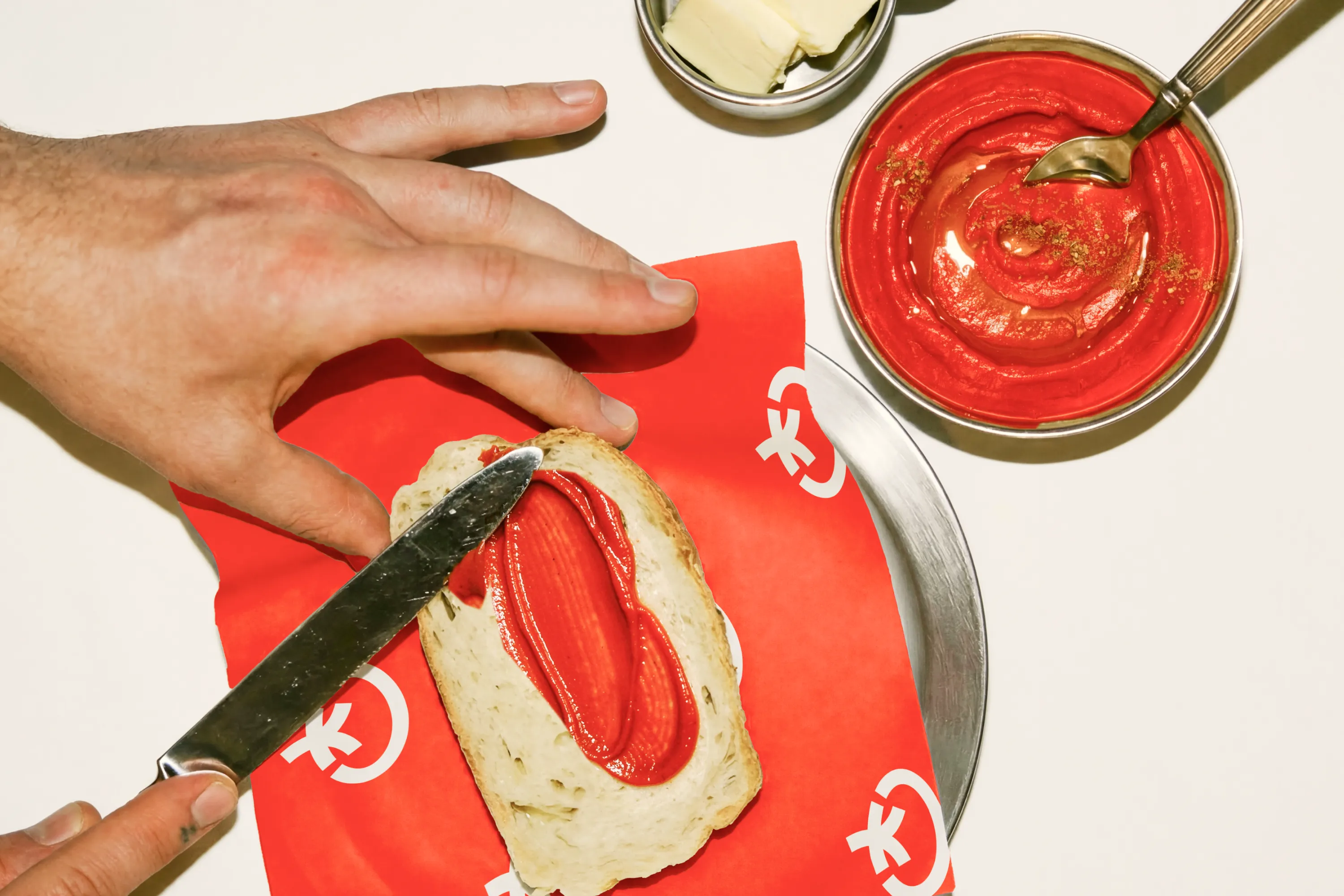 Tomato paste spread on bread beside Toomato packaging.